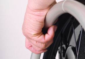 Close-up of a hand gripping the handrim of a wheelchair wheel, illustrating disability awareness.
