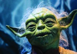 Close-up of a Yoda figure from Star Wars, showing detailed facial features and texture, designed to inspire the force within you, against a blurred blue background.