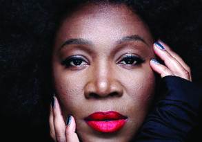Close-up of india arie on her album cover "Worthy," featuring her with red lipstick, polished nails, and both her name and album title prominently displayed.