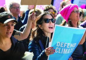 A diverse group of women protesting with signs, one reads "support climate," showcasing activism and engagement.