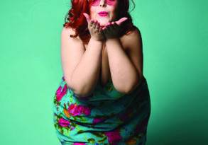 A woman with red hair wearing a floral dress and purple tights, blowing a kiss against a green background, symbolizes the debunking of health misinformation.