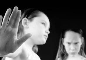 A black and white image of a Mean Girls high school drama scene, featuring a girl with her hand extended forward, palm facing outward, while another girl in the background looks at her intently.