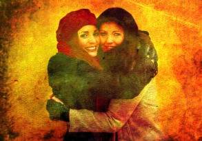 Two women embracing each other and smiling, against a textured orange background, debunking the myth of emotional self-sufficiency. Both are wearing winter attire, including hats and coats.