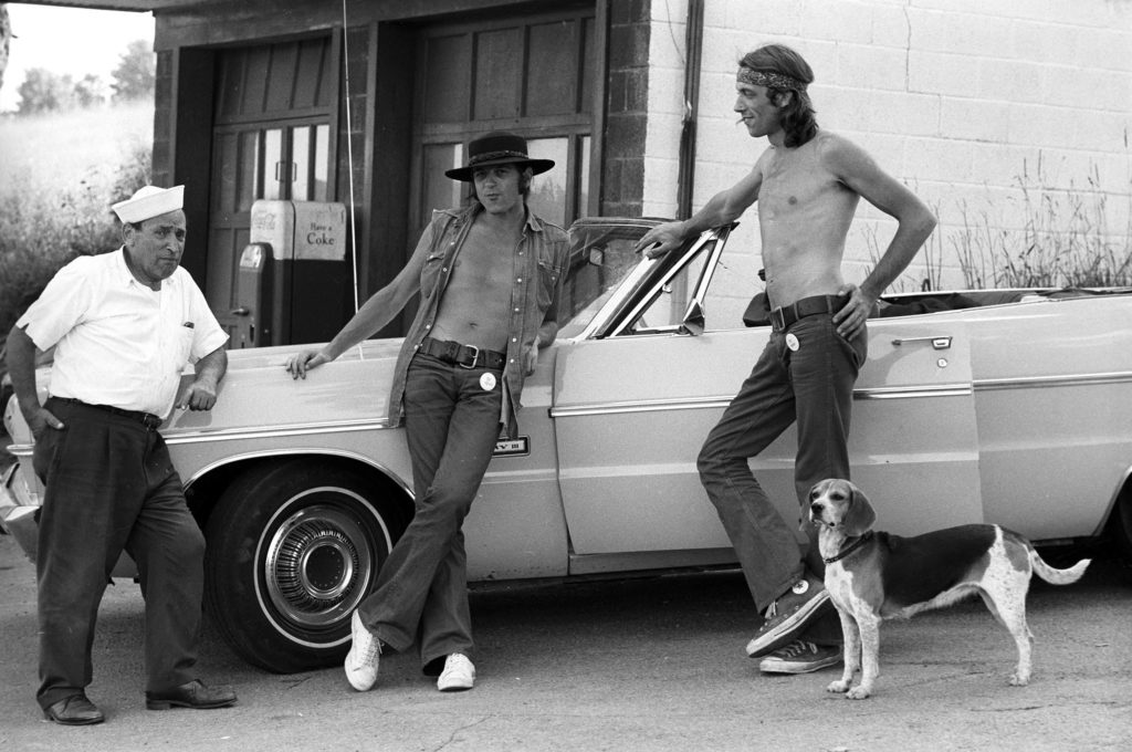 Filmmakers Malcolm Hart (center) and Michael Margetts (right) at the local garage. © Henry Diltz
