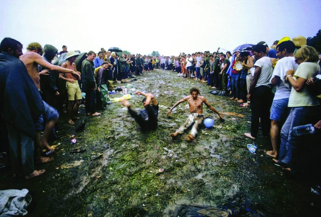 Bethel, New York: Woodstock Music Festival.  Crowd watching young men sliding in the mud. August 1969 ©Tom Miner / The Image Works