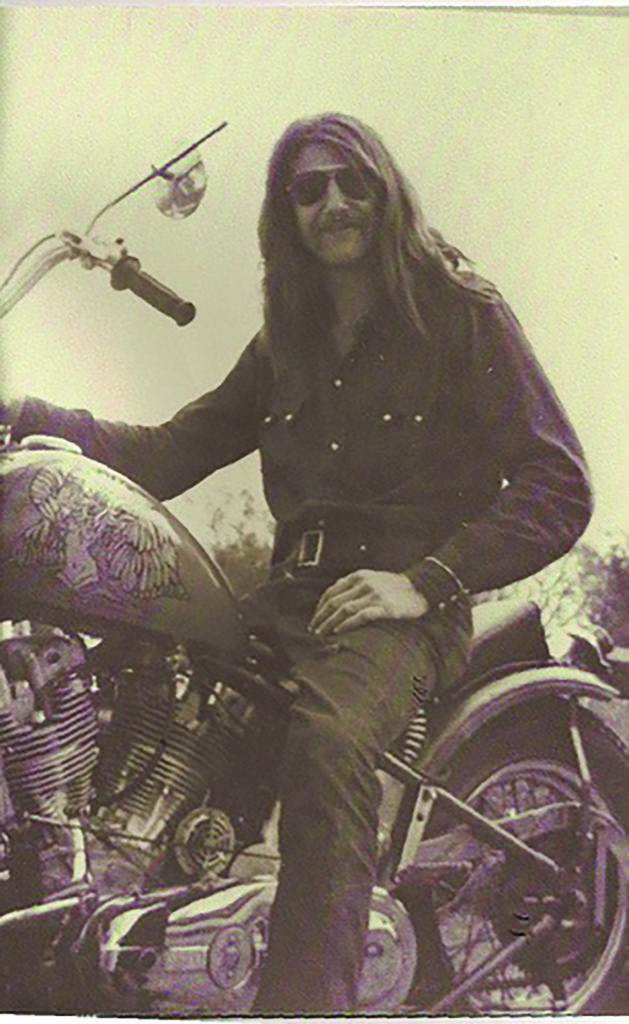 A man with glasses sits on a Harley